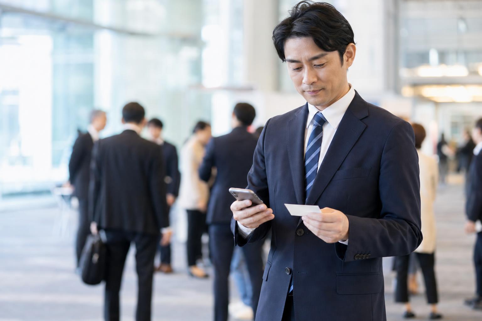 展示会・ビジネスイベント後に受け取った名刺を確認するビジネスパーソン